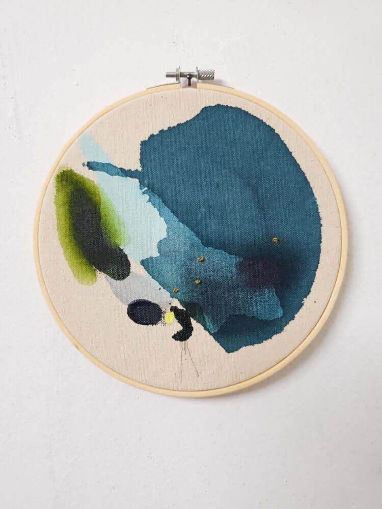 Originalkunstwerk „Forest no.3“ von Alexandra Wolf: Petrolblau, Olivgrün und Dunkelblau auf roher Leinwand im runden Stickrahmen an weißer Wand