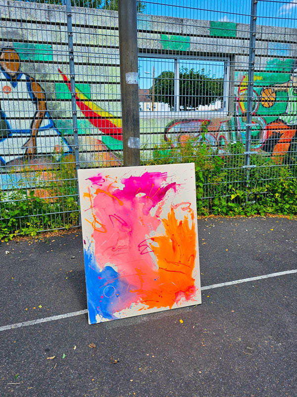 Leuchtende Neonkunst auf einer Staffelei vor einer bunten Wand, inspiriert von Sommerabenden und Aperol Spritz.