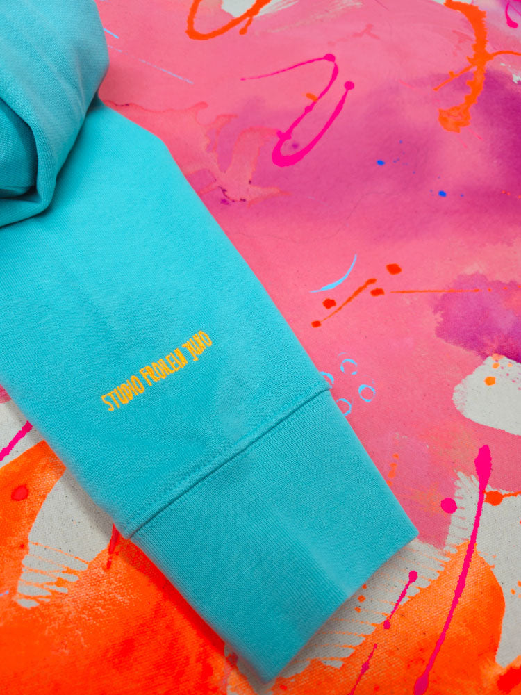 Ärmeldetail des Sweaters mit gelbem Stickschriftzug „Studio Froilein Juno“ – lasst uns weiterhin Farbe bekennen, denn das geht Kunst was an.