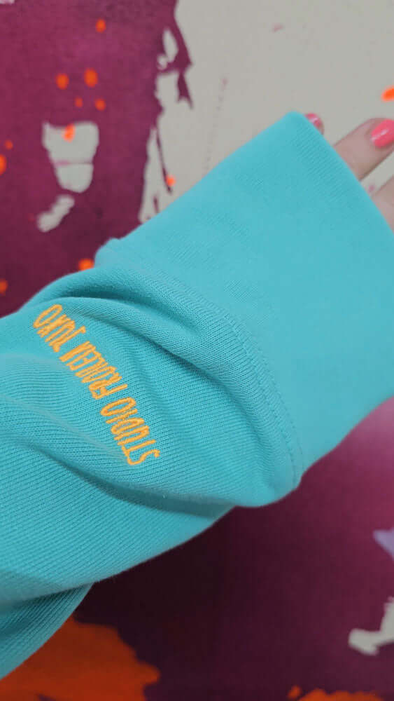 Nahaufnahme der Stickerei in Neon Orange am Ärmel auf türkisem Stoff – dezente Details für einen einzigartigen Look von Studio Froilein Juno x Alexandra Wolf