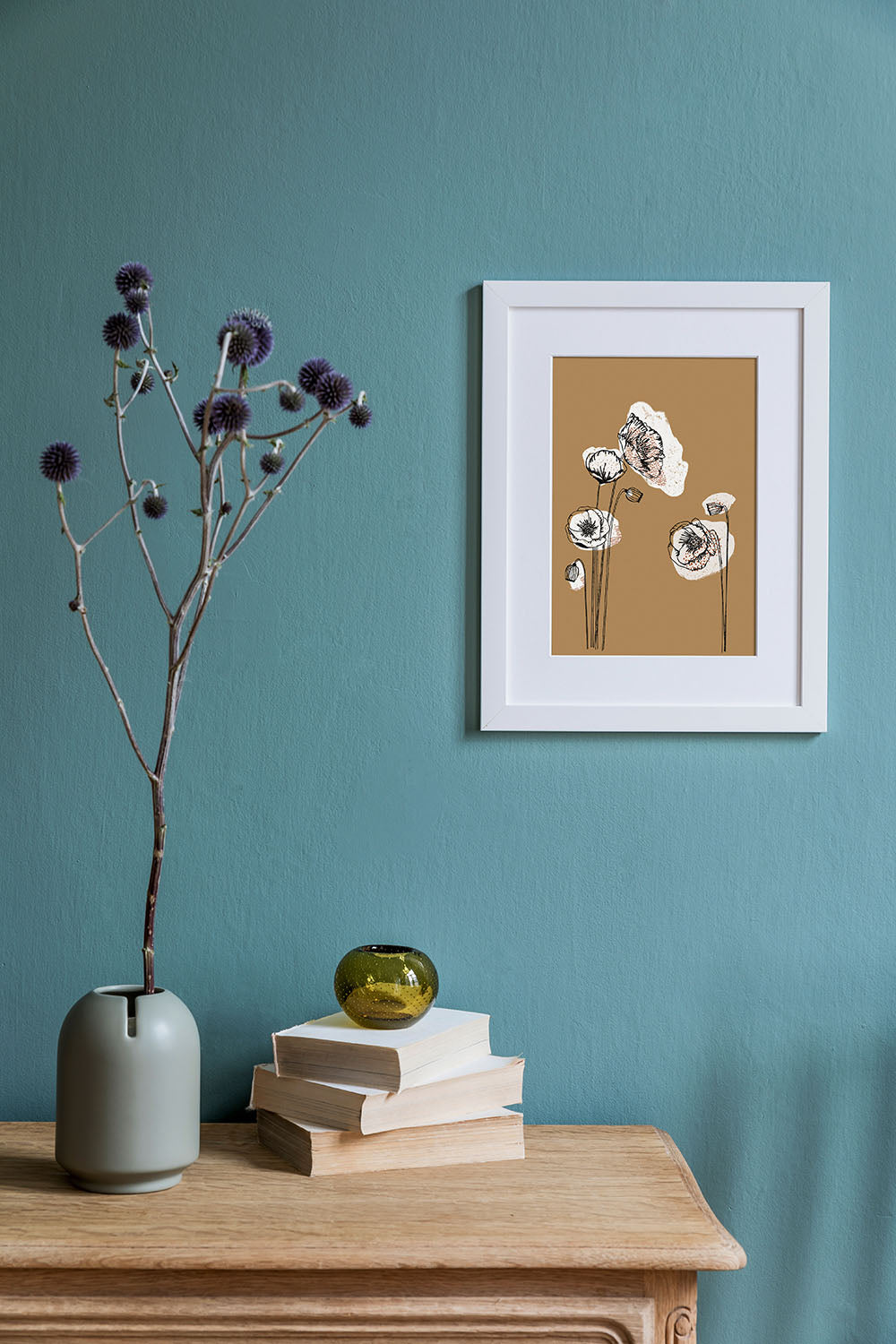 Kunstdruck mit illustrierten Mohnblumen auf gelbem Untergrund über einem Sideboard mit Büchern und einer Vase