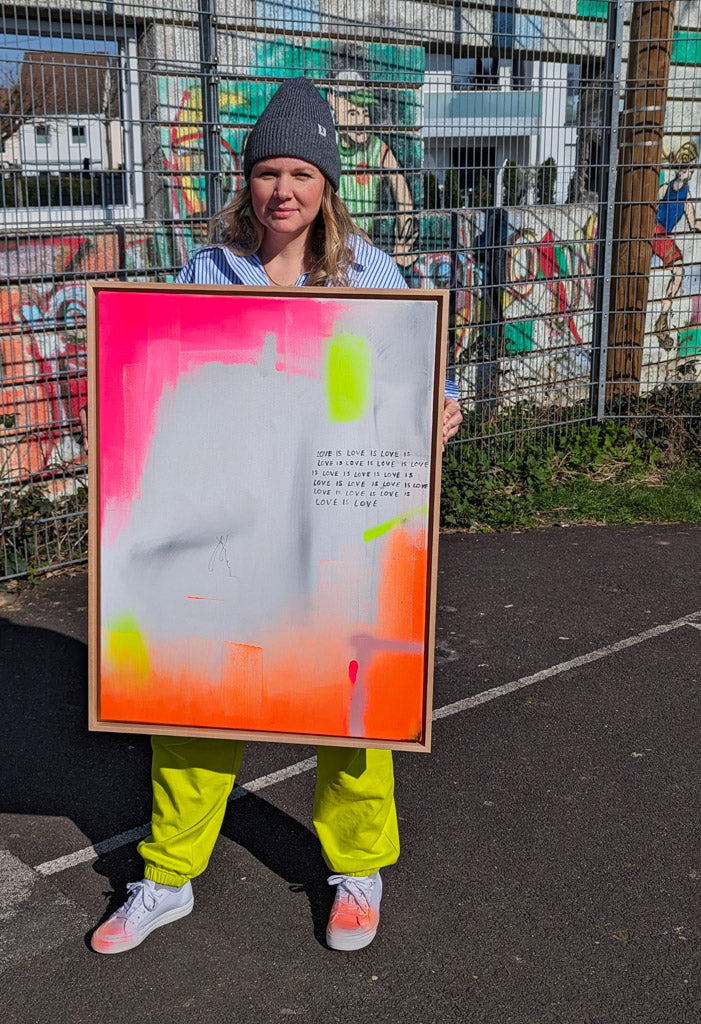 Alexandra Wolf mit ihrem Bild „Love is love“ vor einer Graffiti-Wand in Bonn