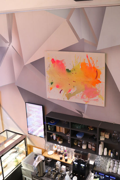 „Colorful world no.1“ von Studio Froilein Juno hängt in einem Café über der Theke mit Kuchenvitrine, Kunst im Raum