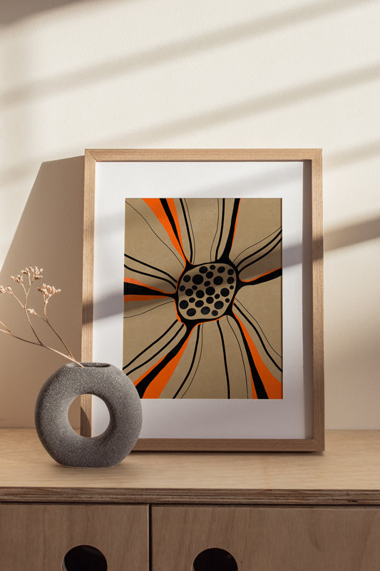 Gerahmter Kunstdruck mit abstrakter Blume in Orange und Schwarz im Risografie Look auf Holzkommode im warmen Interior